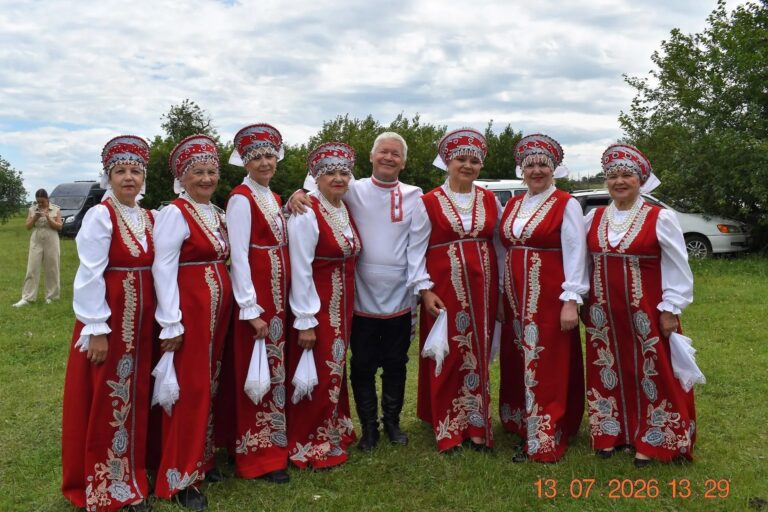 Вокальный ансамбль "Заряночка". Девушки в красных народных костюмах, по центру стоит гармонист